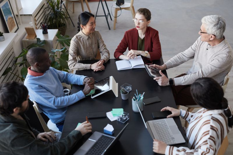 Diverse group of business people sitting at table during briefing meeting in office