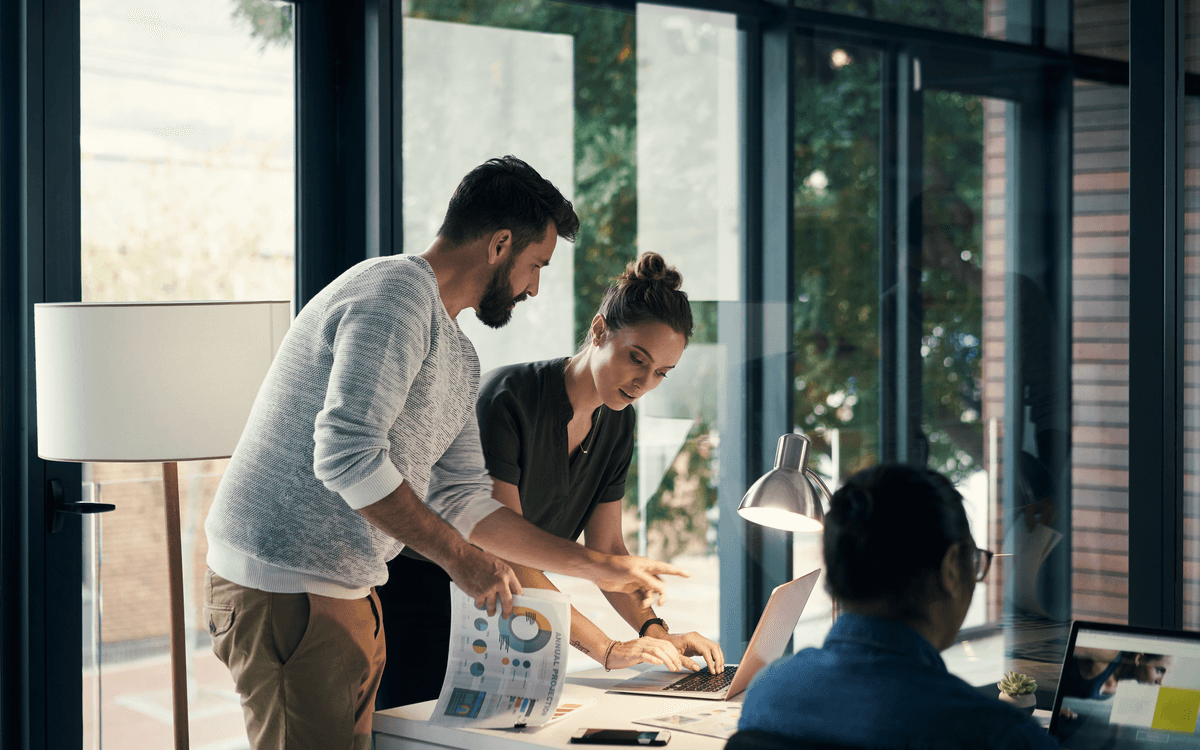 Group of workers working together around a table using laptops