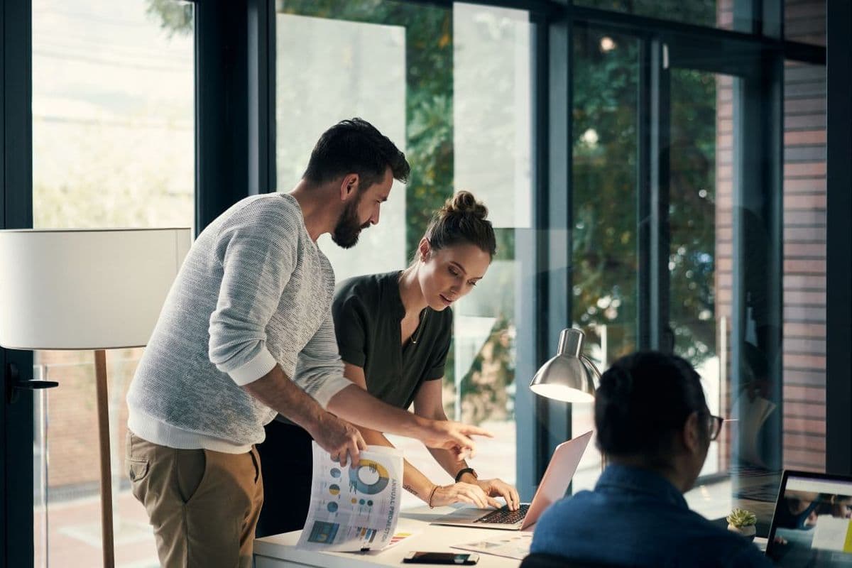 Group of workers working together around a table using laptops