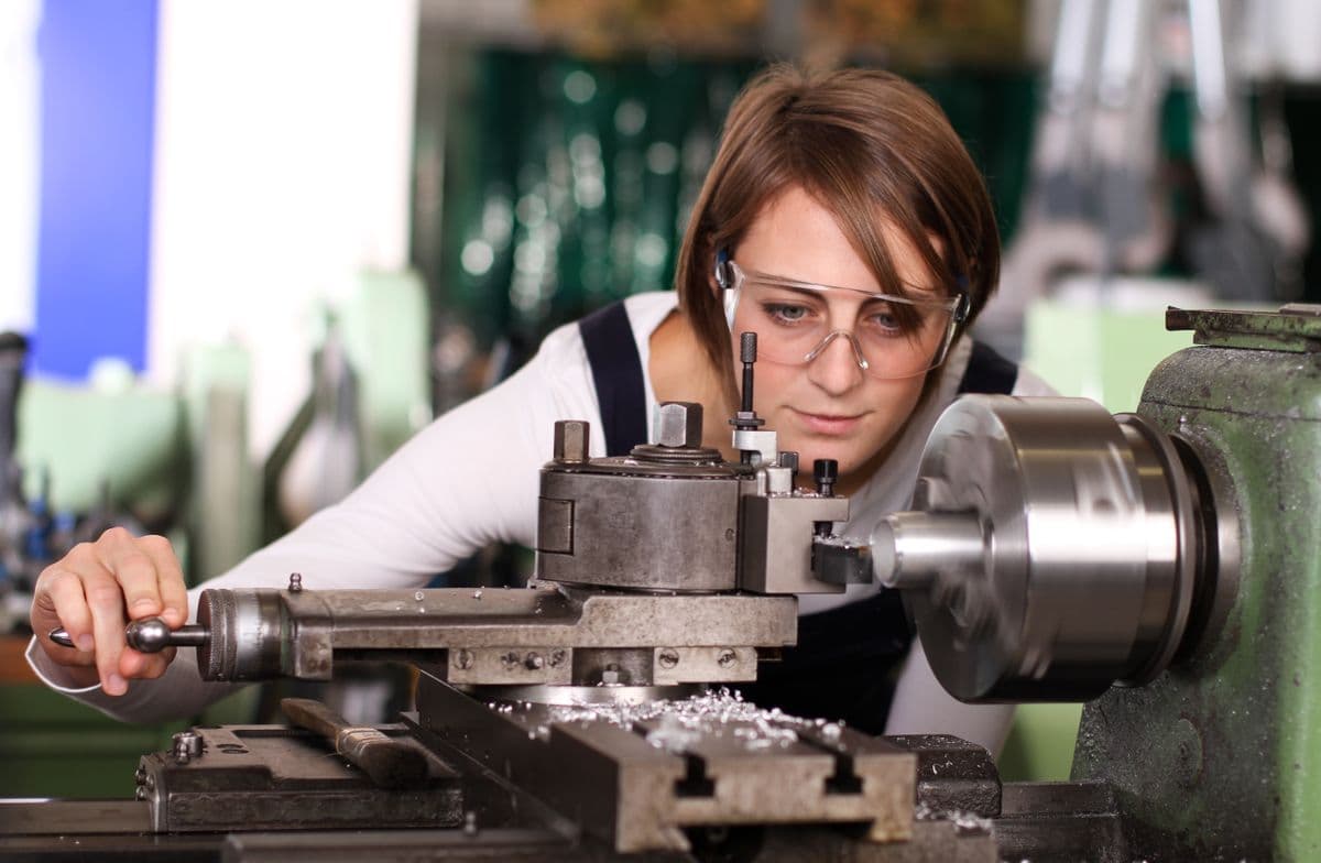 Young woman working the metal working lathe