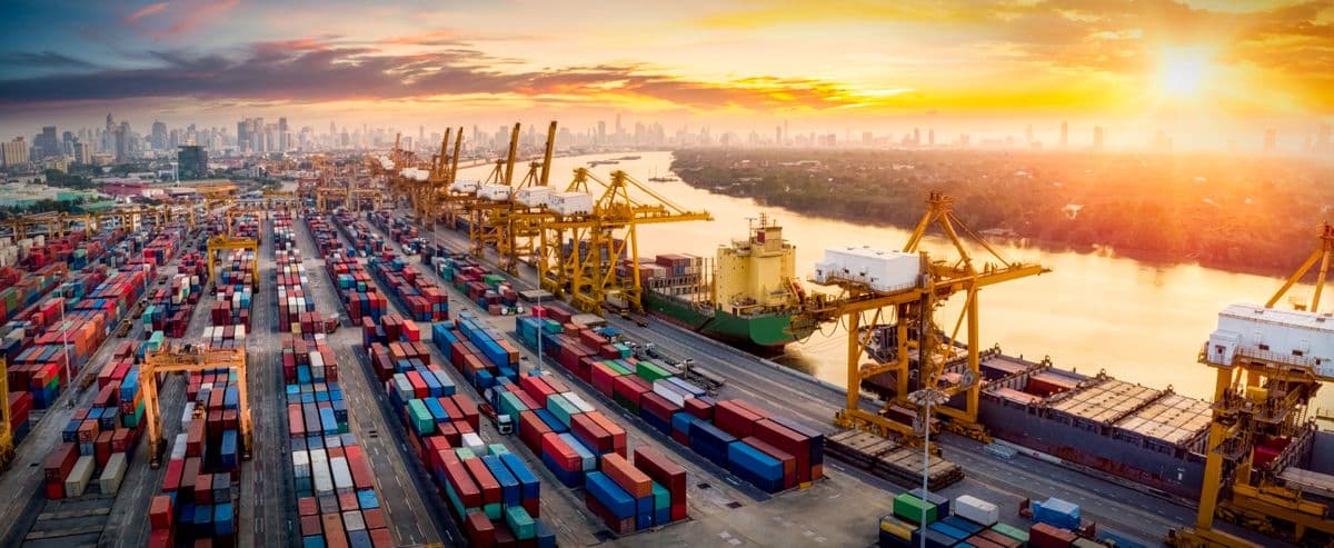 Logistics and transportation of Container Cargo ship and Cargo plane with working crane bridge in shipyard at sunrise, logistic import export and transport industry background