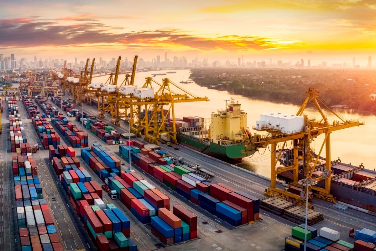 Logistics and transportation of Container Cargo ship and Cargo plane with working crane bridge in shipyard at sunrise, logistic import export and transport industry background