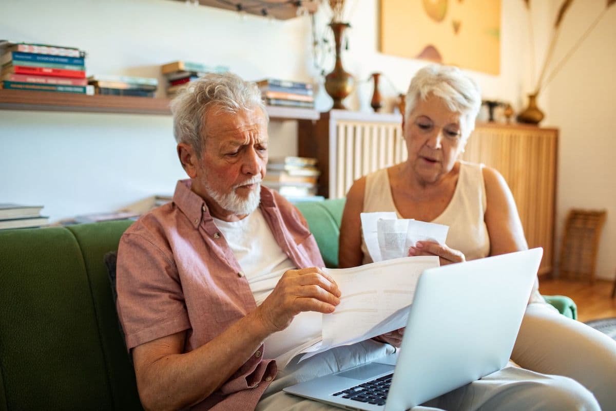 Senior couple reviewing utility bills at home with laptop