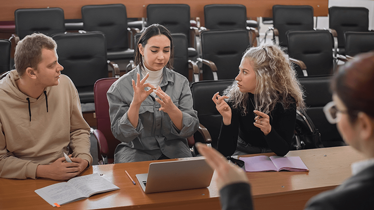 Image of teacher and students communicating using sign language in the classroom