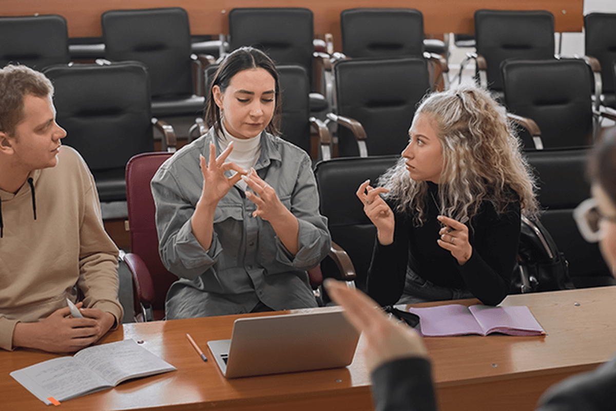 Image of teacher and students communicating using sign language in the classroom
