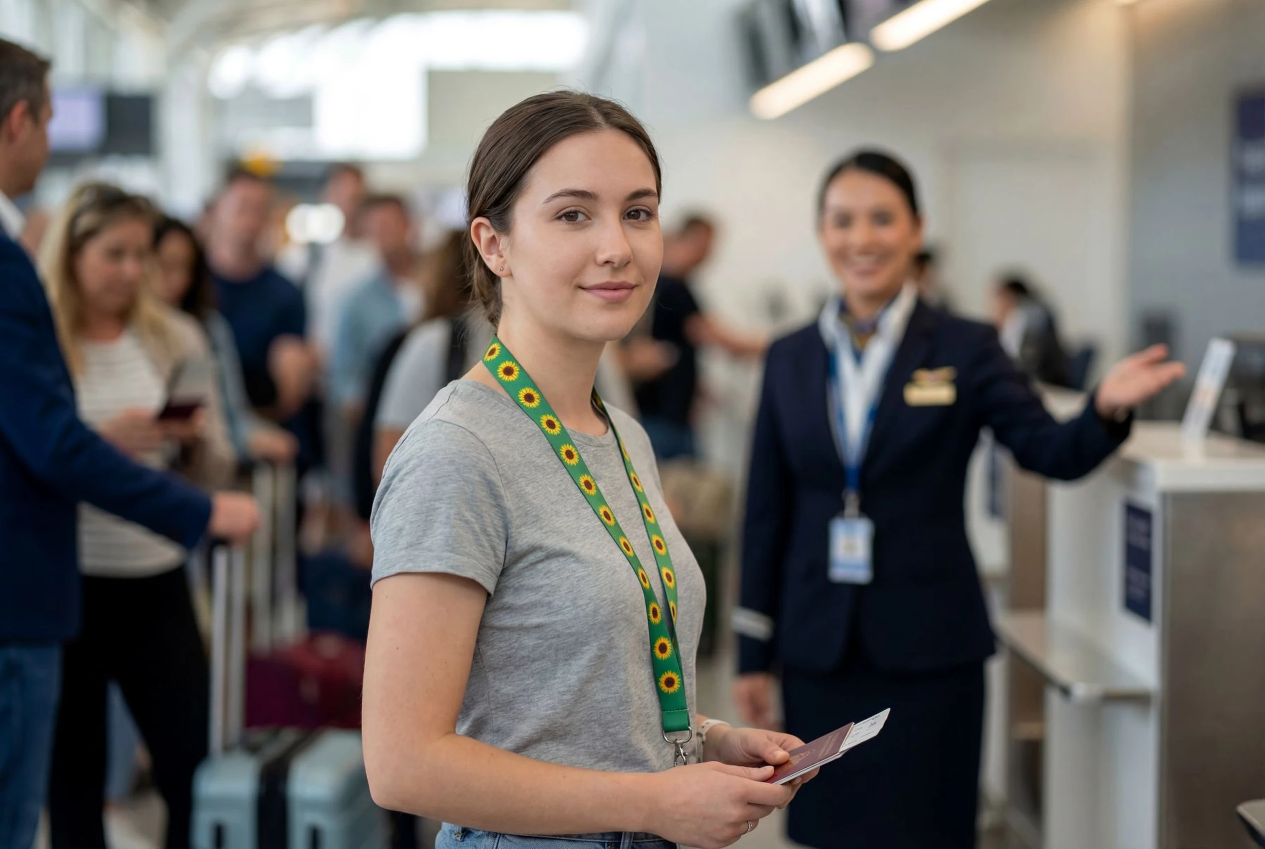 AI generated image of young woman at airport check-in counter, holding boarding pass, wearing sunflower lanyard; staff member gestures in the background.